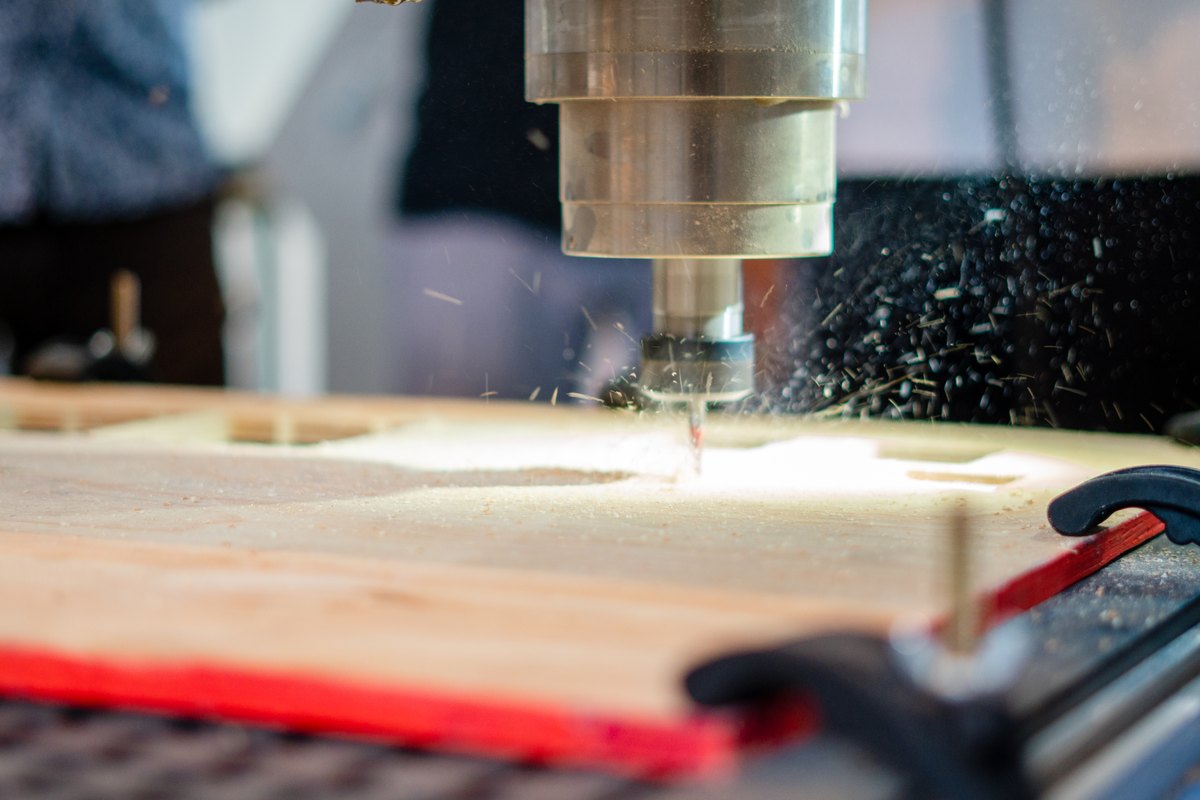 Close-up of a CNC cutting tool machining a wooden panel